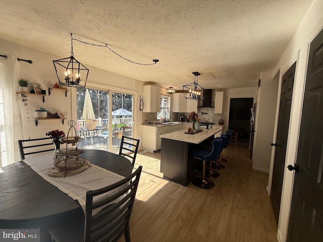 dining room with light wood-style flooring, a chandelier, and a textured ceiling