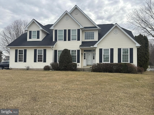 traditional home with a shingled roof and a front lawn