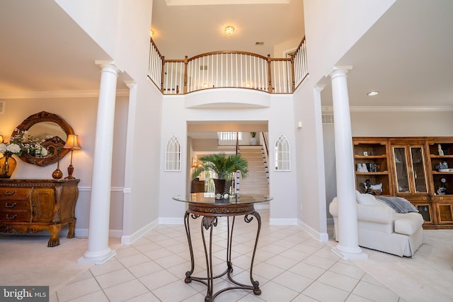 entrance foyer featuring light tile patterned floors, ornamental molding, and decorative columns