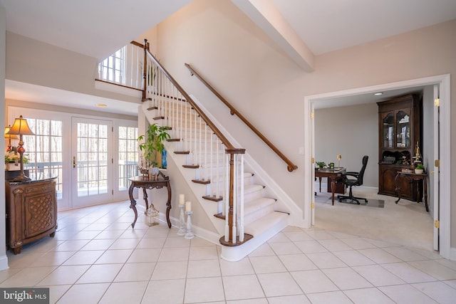 staircase featuring tile patterned flooring, a high ceiling, baseboards, and carpet flooring