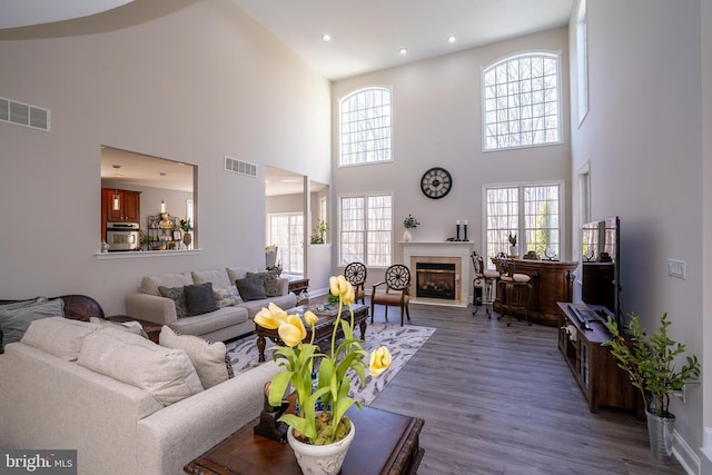 living room with a fireplace, visible vents, wood finished floors, and recessed lighting