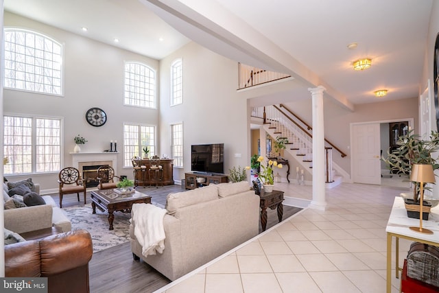 living room featuring tile patterned flooring, stairs, ornate columns, a fireplace, and recessed lighting