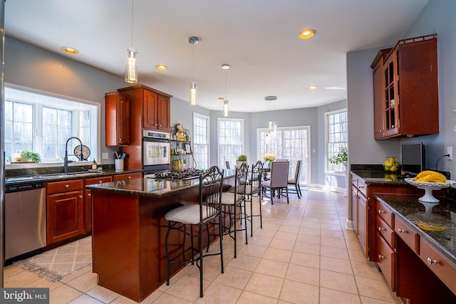 kitchen featuring recessed lighting, a sink, a kitchen breakfast bar, appliances with stainless steel finishes, and glass insert cabinets