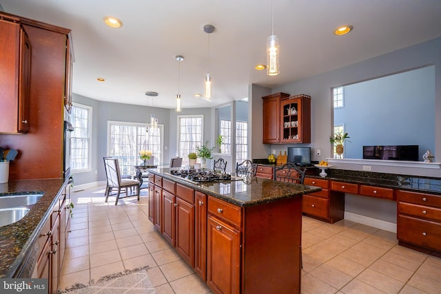 kitchen with light tile patterned floors, glass insert cabinets, gas cooktop, built in desk, and recessed lighting