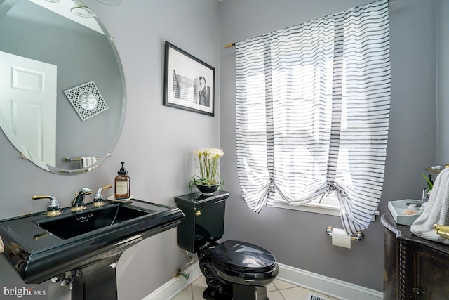 bathroom featuring tile patterned flooring, baseboards, a sink, and toilet