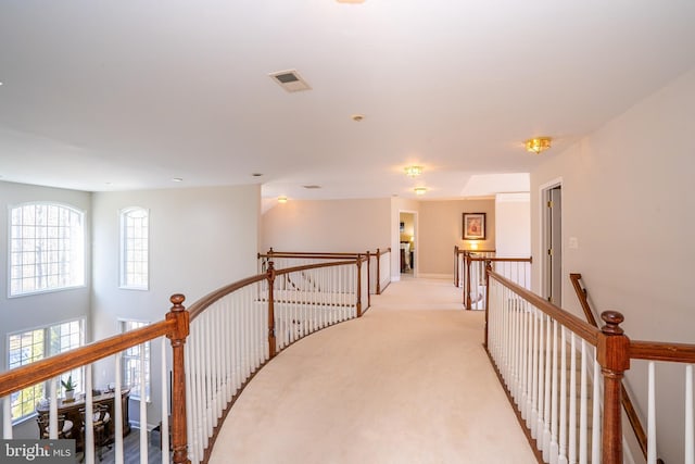 hall featuring visible vents, baseboards, an upstairs landing, and light colored carpet