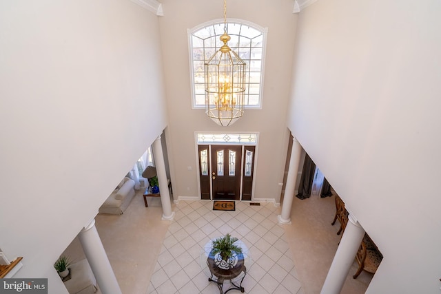 foyer entrance featuring an inviting chandelier, tile patterned flooring, a high ceiling, and baseboards