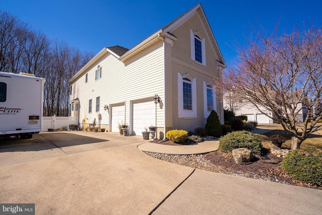 view of property exterior featuring a garage, driveway, and fence