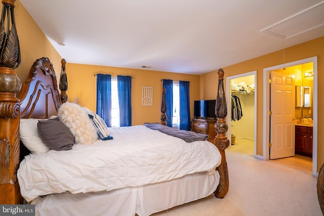 bedroom featuring a closet, a walk in closet, carpet, ensuite bath, and attic access