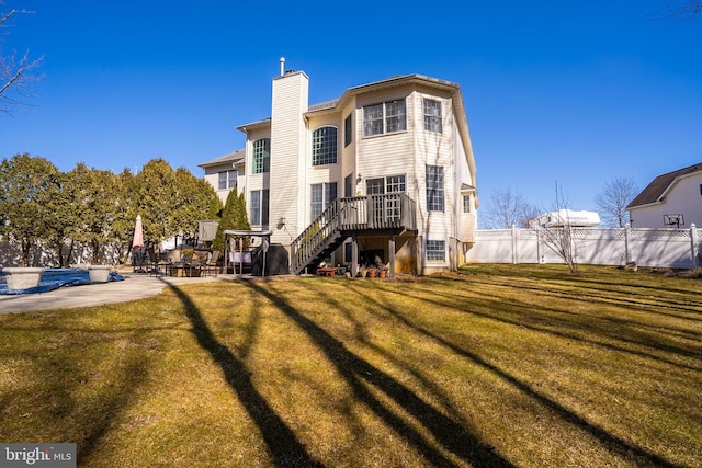 rear view of house with a chimney, stairs, fence, a deck, and a yard