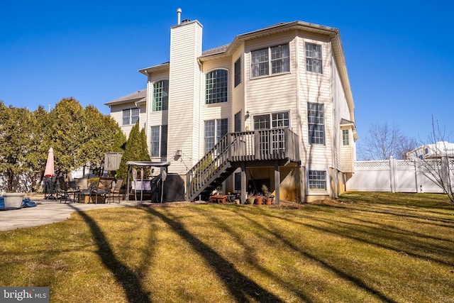 back of house featuring a patio, fence, a yard, stairway, and a chimney