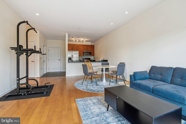 living room featuring light wood finished floors, baseboards, and recessed lighting