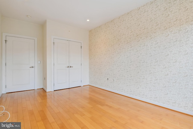 unfurnished bedroom featuring baseboards, a closet, wood finished floors, and recessed lighting