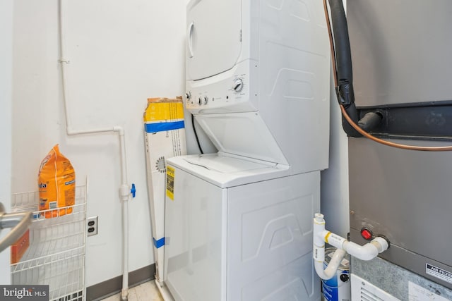 clothes washing area featuring heating unit, laundry area, and stacked washer / drying machine