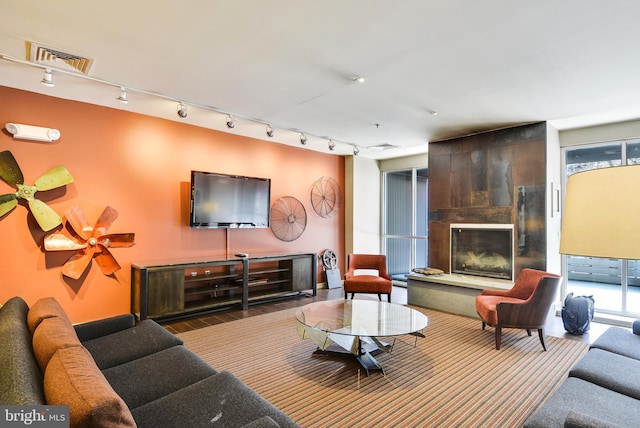 living room featuring visible vents, a tiled fireplace, and wood finished floors