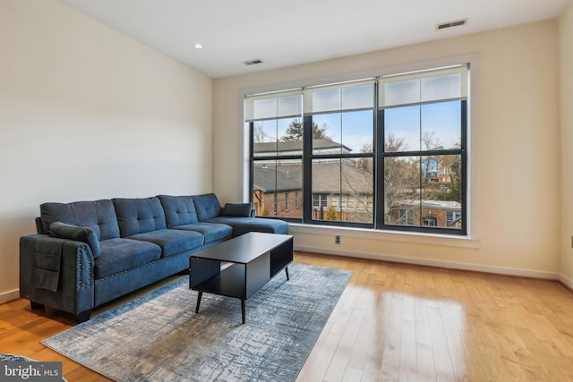 living area with light wood-type flooring, visible vents, and baseboards