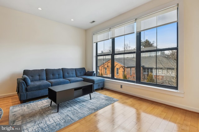 living area with light wood-type flooring, visible vents, baseboards, and recessed lighting