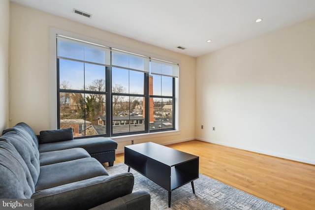 living room featuring baseboards, visible vents, wood finished floors, and recessed lighting