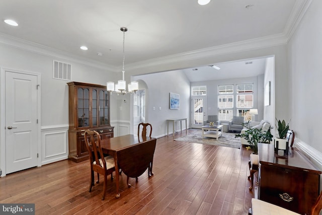 dining area featuring crown molding, visible vents, arched walkways, and wood finished floors