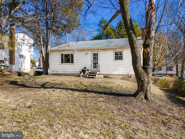 rear view of house featuring entry steps and fence