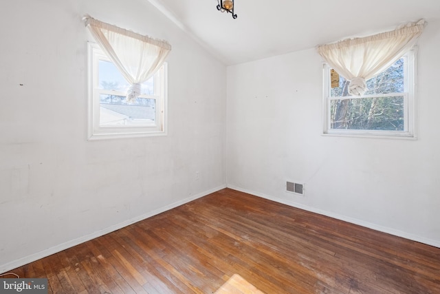 unfurnished room featuring plenty of natural light, wood-type flooring, visible vents, and baseboards