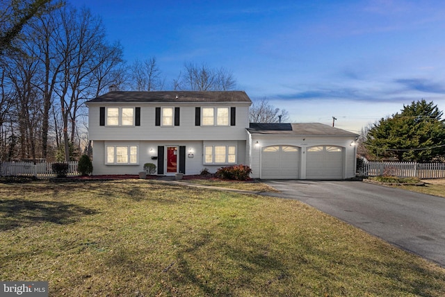 colonial-style house featuring a garage, a yard, aphalt driveway, and fence