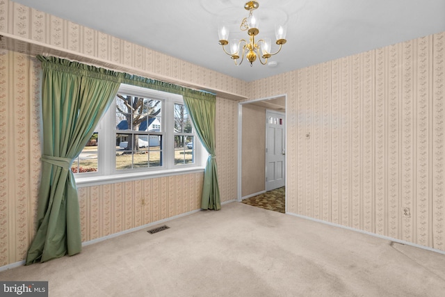 spare room featuring an inviting chandelier, visible vents, carpet flooring, and wallpapered walls