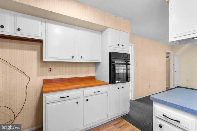 kitchen with light countertops, oven, light wood finished floors, and white cabinetry