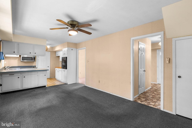 kitchen with light countertops, light colored carpet, oven, and stainless steel microwave