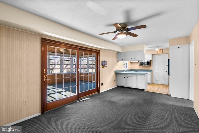 kitchen featuring light colored carpet, stainless steel microwave, visible vents, and wallpapered walls