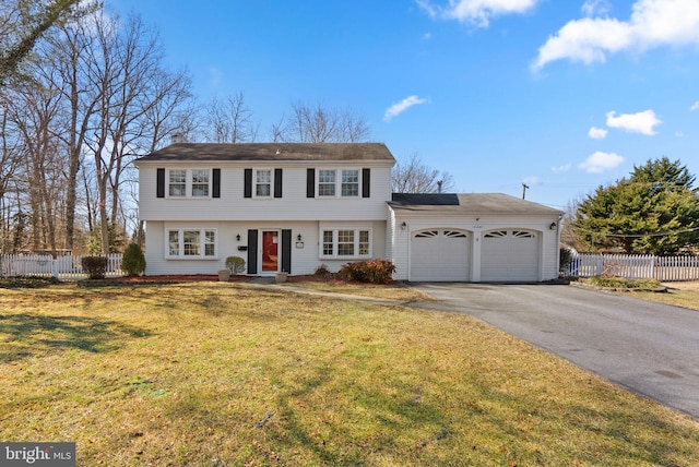 colonial inspired home with aphalt driveway, an attached garage, fence, and a front yard