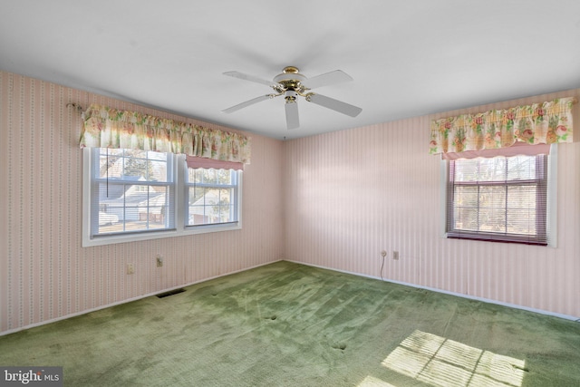 carpeted empty room with wallpapered walls, ceiling fan, and visible vents