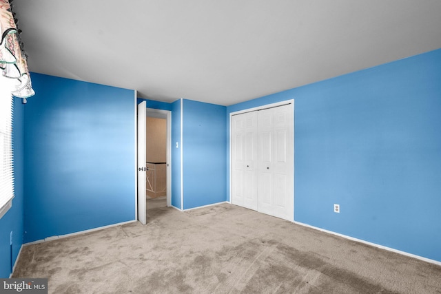 unfurnished bedroom featuring baseboards, a closet, and light colored carpet