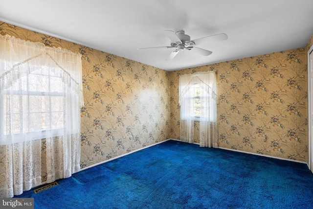 carpeted spare room with wallpapered walls, ceiling fan, visible vents, and baseboards