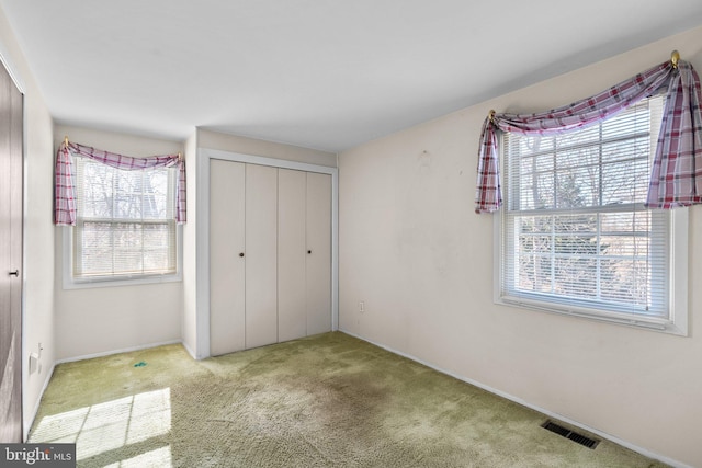 unfurnished bedroom with light carpet, a closet, and visible vents