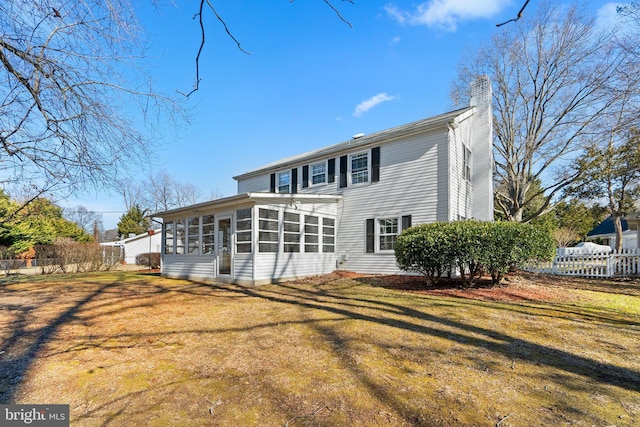 back of property with a yard, a chimney, fence, and a sunroom