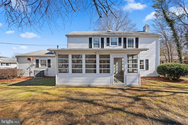 view of front of home with central AC, a chimney, a front yard, and a sunroom