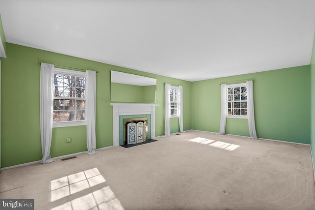 unfurnished living room with visible vents, a fireplace, light carpet, and baseboards