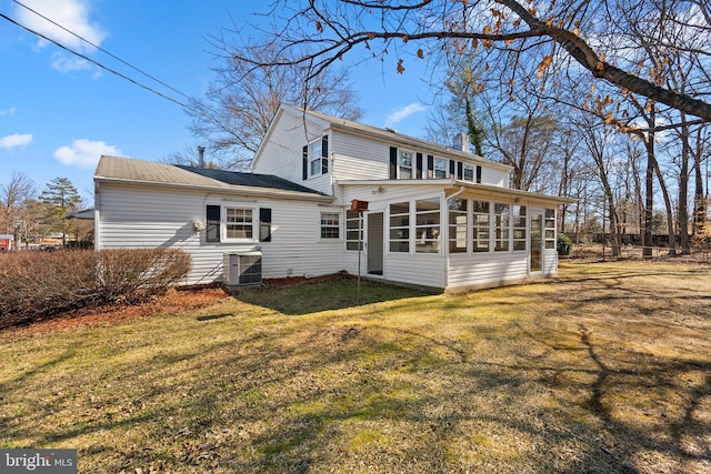 back of house featuring a lawn, a chimney, a sunroom, and central air condition unit