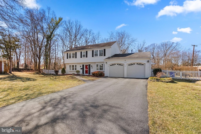 colonial-style house featuring an attached garage, a front lawn, fence, and aphalt driveway