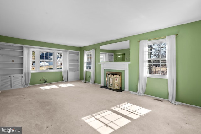 unfurnished living room featuring light carpet, a fireplace, visible vents, and baseboards