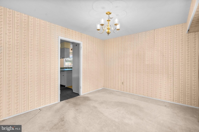 spare room with a notable chandelier, carpet, and wallpapered walls