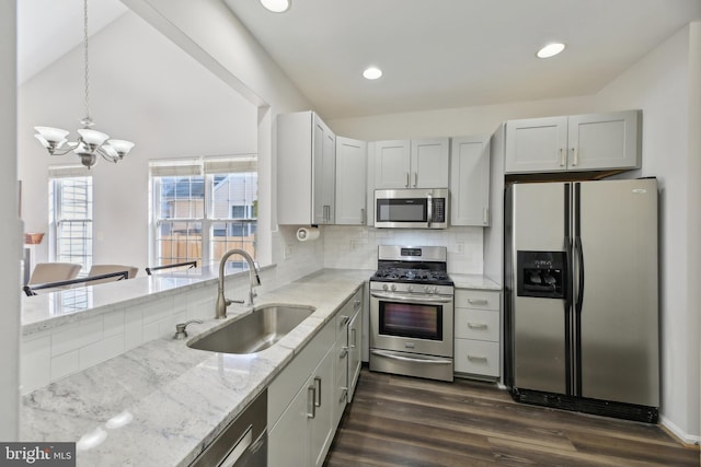 kitchen with stainless steel appliances, dark wood-type flooring, a sink, backsplash, and light stone countertops