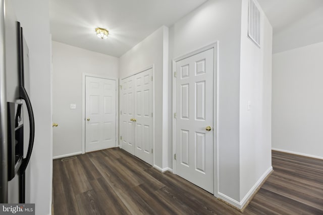 hallway featuring dark wood-style floors, visible vents, and baseboards