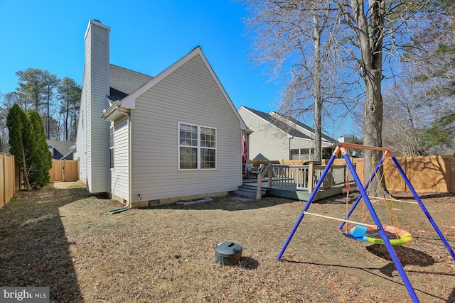 exterior space with a fenced backyard, a chimney, crawl space, a wooden deck, and a playground