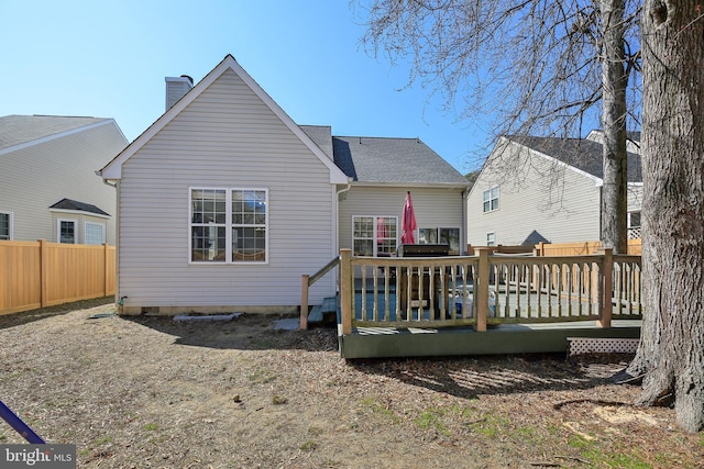 rear view of house featuring a chimney, fence, and a deck