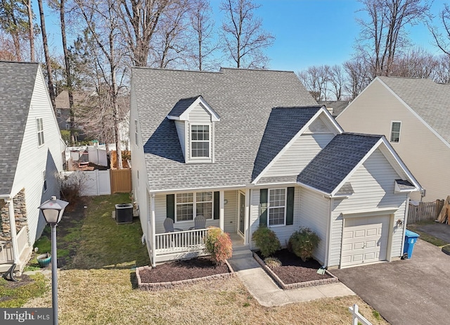 cape cod-style house with roof with shingles, fence, a porch, central AC, and a front yard