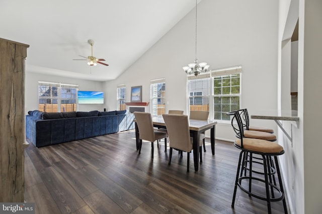 dining room with high vaulted ceiling, dark wood finished floors, and ceiling fan with notable chandelier