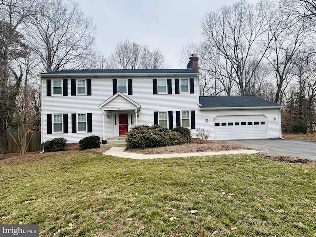 view of front facade with a garage, a chimney, aphalt driveway, and a front yard