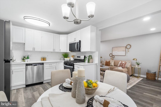 kitchen featuring stainless steel appliances, pendant lighting, light countertops, and white cabinetry